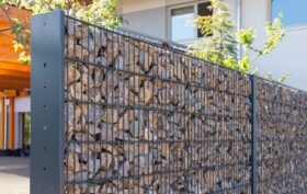 A modern gabion fence constructed from stones creates an elegant boundary