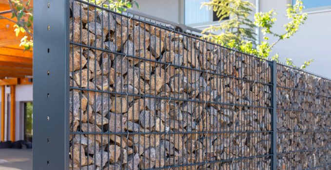 A modern gabion fence constructed from stones creates an elegant boundary